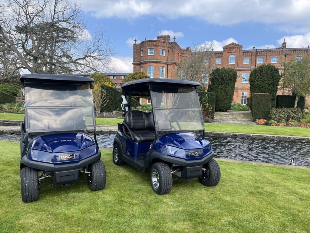 Two Club Car Tempo cars in front o the mansion at The Grove. The venue is the first golf resort in the UK to install golf cars with Bluetooth speakers